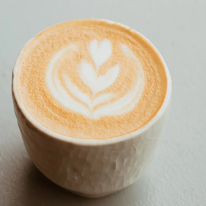Cold Brew Pumpkin Spice Latte mit Latte Art auf einem weißen Untergrund stehend 