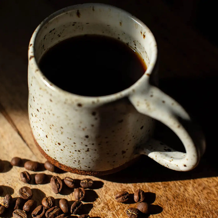 Eine gefüllte Kaffeetasse mit Kaffeebohnen auf einem Holztisch
