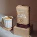 Eine Packung J. Hornig Alles Arabica Kaffee mit einer Cappuccinotasse auf hellem Untergrund und braunem Hintergrund