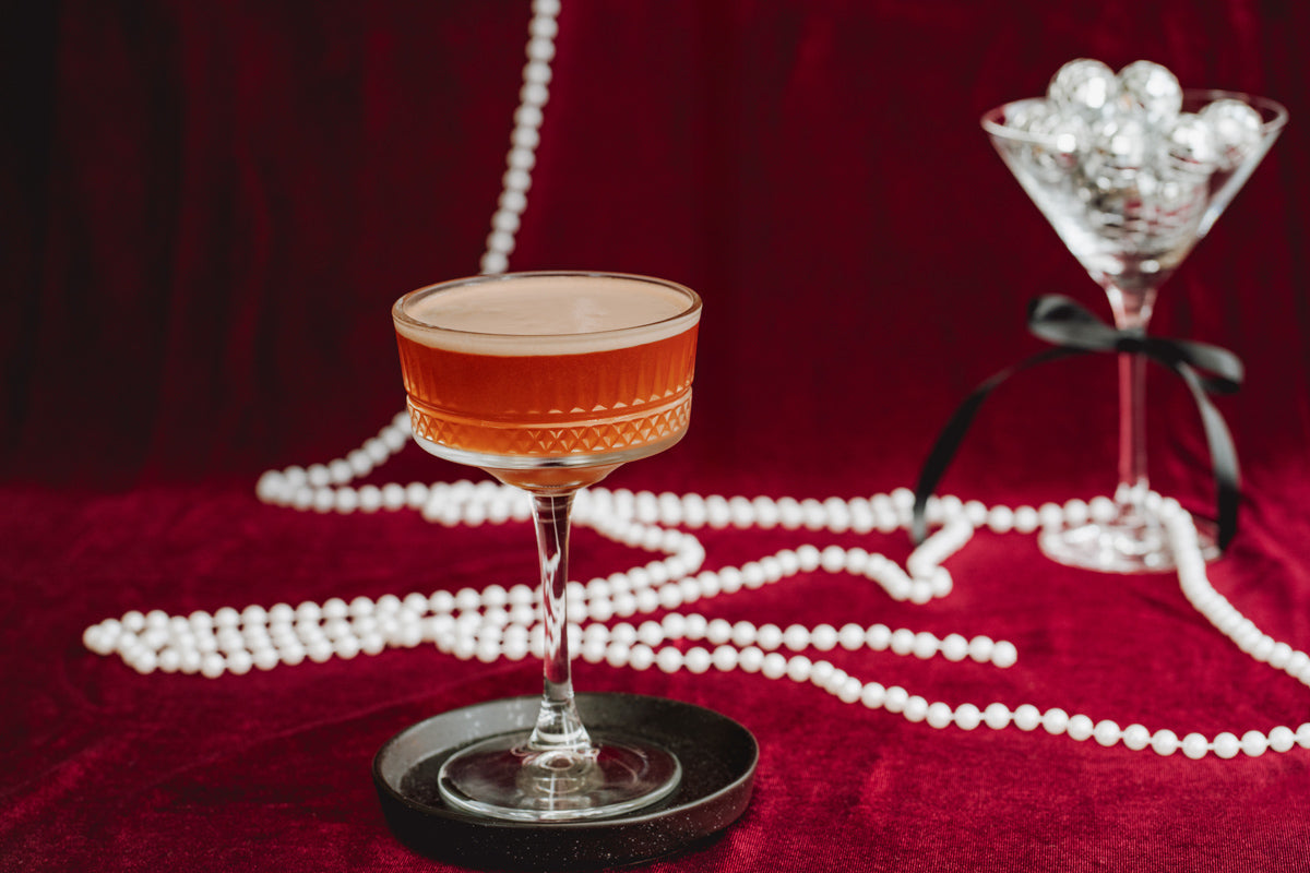 Cold Brew Pornstar Martini im Glas mit Perlen und Discokugeln im Hintergrund.