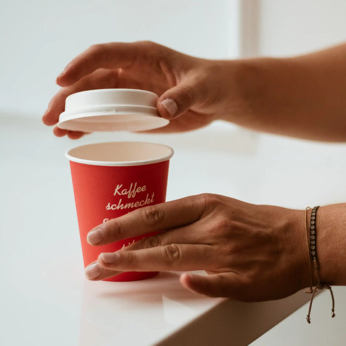 Zwei Hände halten einen J. Hornig coffee-to-go Becher.