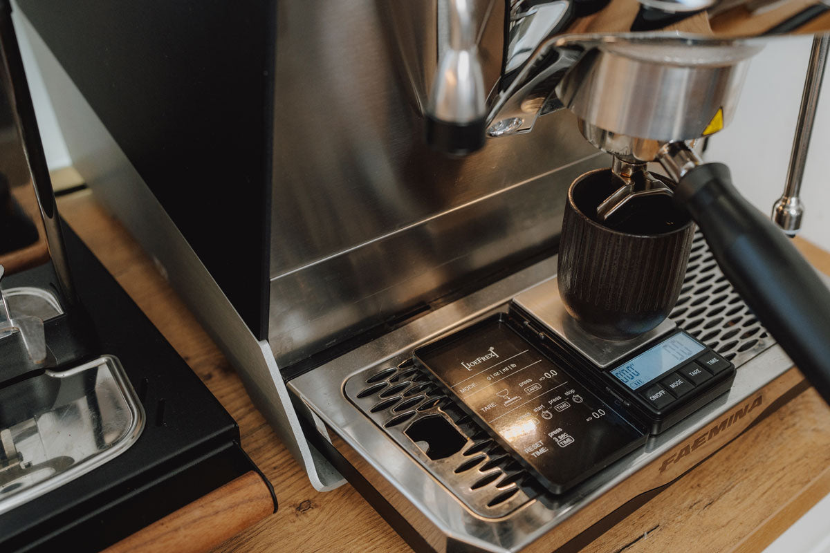 Man sieht eine Siebträgermaschine, unter der Kaffeetasse steht eine Espresso-Waage, welche ihm J. Hornig Onlineshop erhältlich ist. 
