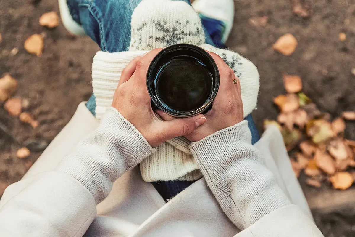 Zwei Hände halten eine Kaffeetasse.