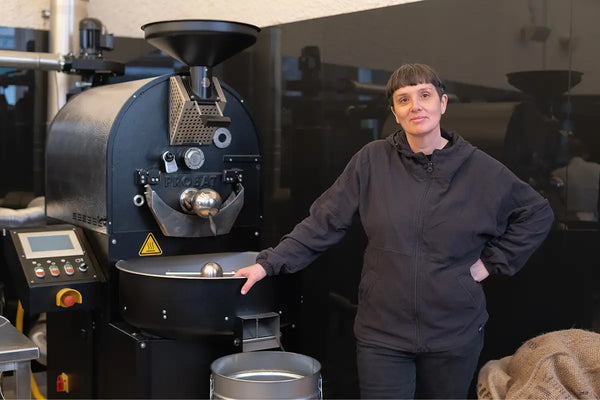Eine Person steht neben einer modernen Röstmaschine.