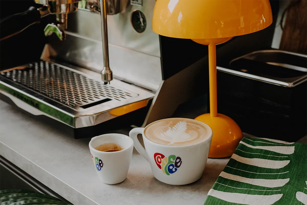 Eine Espressotasse und eine Milchkaffeetasse von J. Hornig in Pride Edition 2024 neben einer Siebträgermaschine