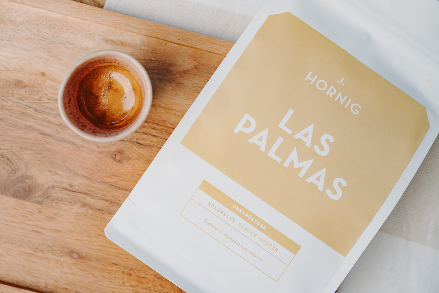 Packung J. Hornig Las Palmas neben einer Espressotasse auf einem Holzbrett.