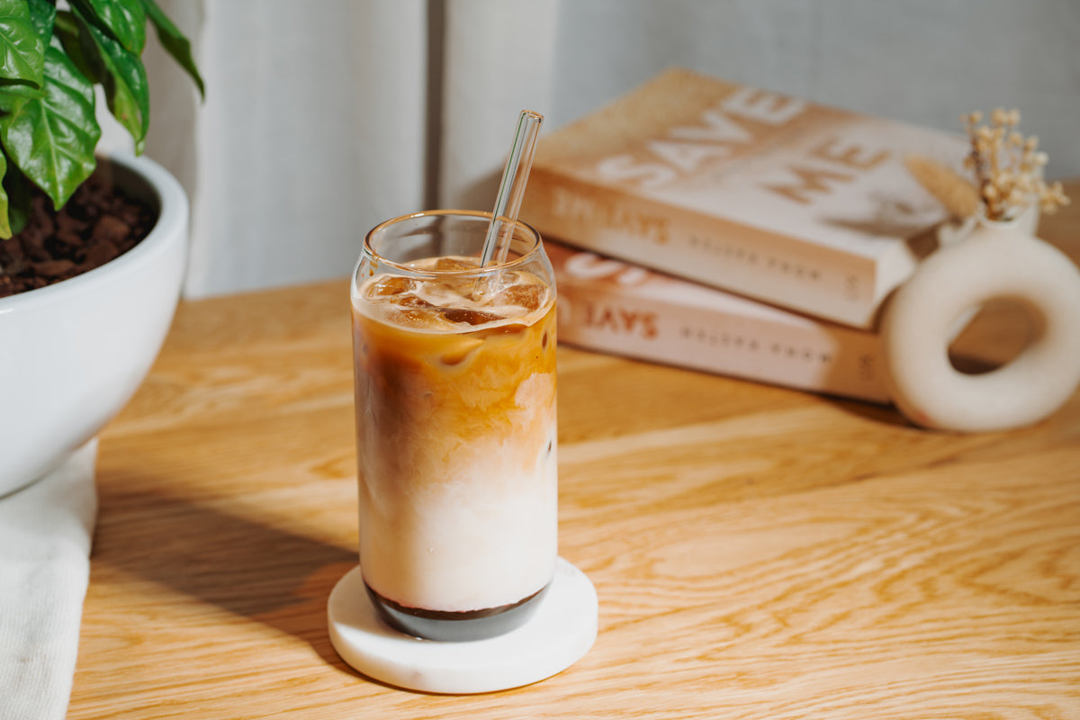 Ein Glas steht auf einem Tisch, darin befindet sich ein Cherry-Vanilla Iced Latte mit J. Hornig Kaffee.