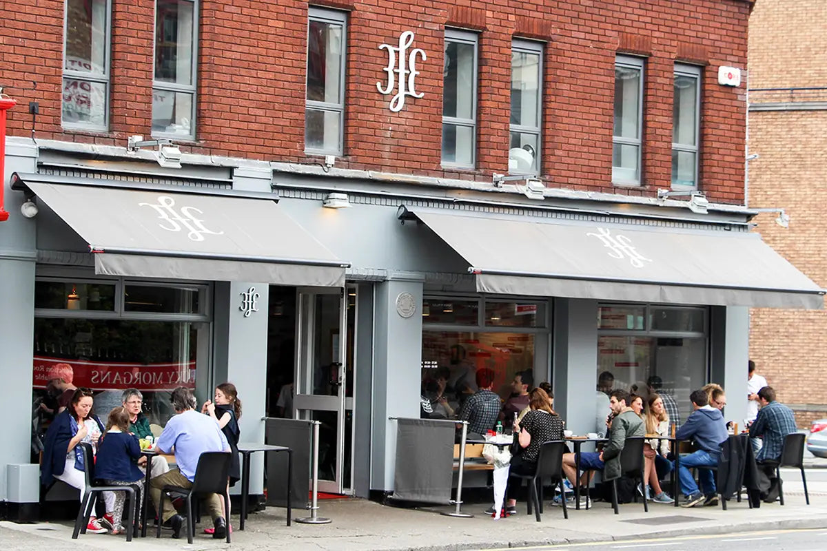 Coffeeshop 3FE Dublin von außen mit Leuten die vor dem Coffeeshop sitzen